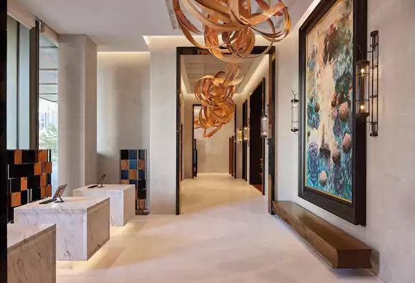 木材与铜材交织成河流的曲线,悬空于挑高空间中,与墙面的抽象画作形成对话 木材与铜材交织成河流的曲线,悬空于挑高空间中,与墙面的抽象画作形成对话