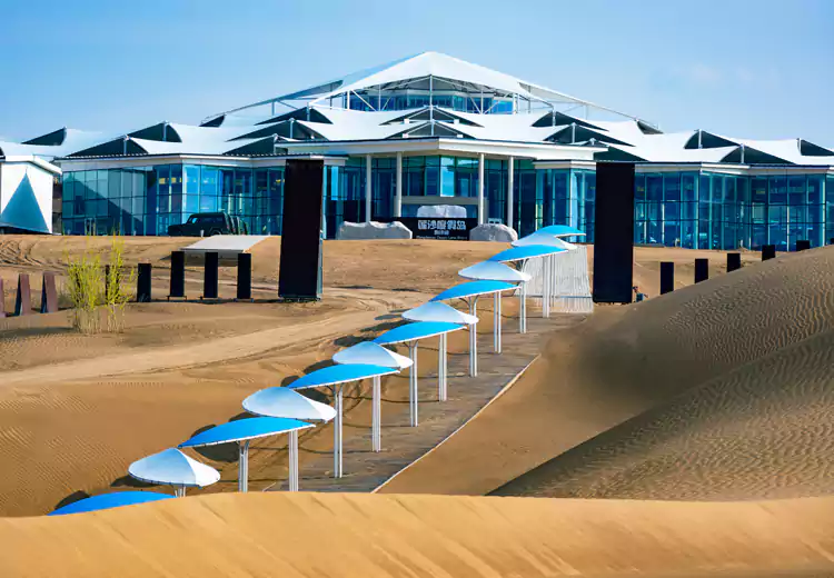 以膜结构覆盖的屋顶平台构成了一片片 “花瓣”,三角形的旋转重复造型在沙漠中格外醒目 以膜结构覆盖的屋顶平台构成了一片片 “花瓣”,三角形的旋转重复造型在沙漠中格外醒目