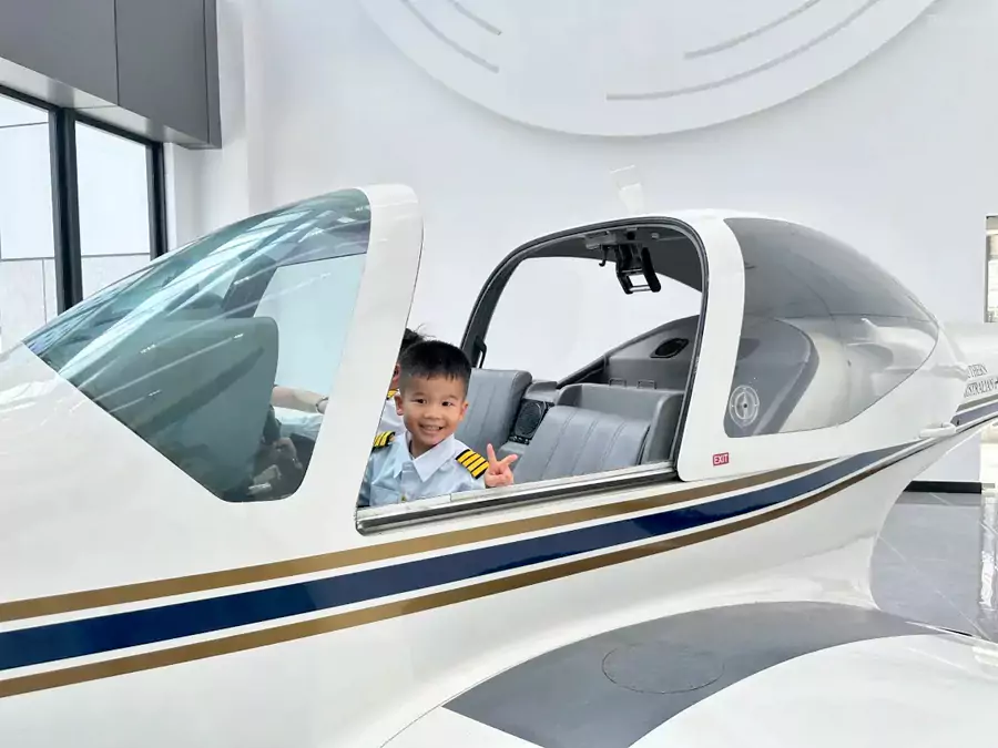 穿上小小机长服，坐在模拟驾驶舱里