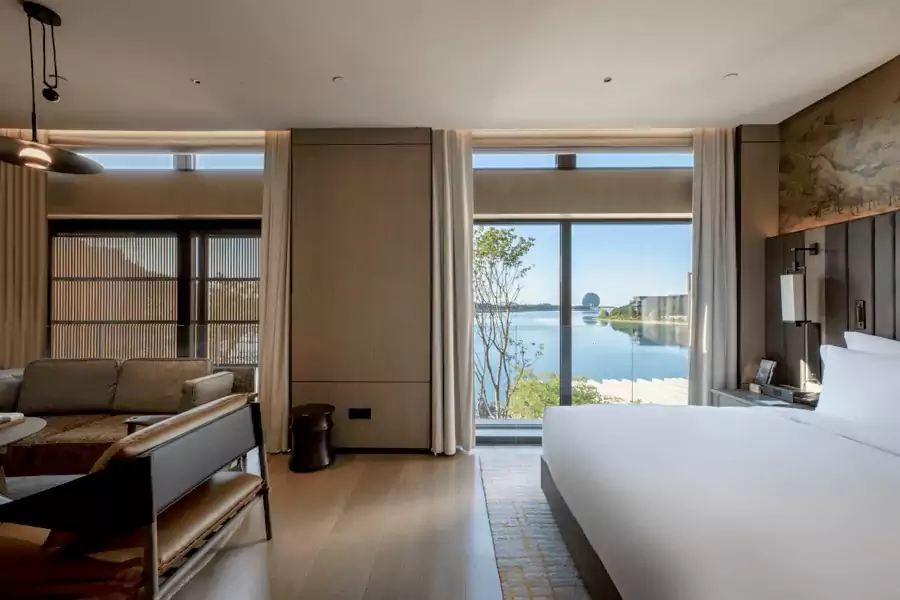 木质元素铺满房间，柔和的灯光透过纱帘洒下，巨幅山水画挂在床头